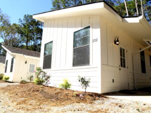 White board-and-batten rental cabin among tall pine trees at Fireside RV Resort in Ponchatoula Louisiana